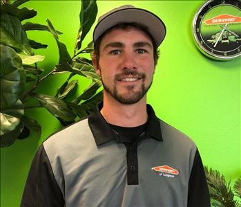a young man in a SERVPRO shirt in front of a green background