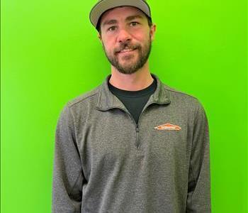 a young man in a SERVPRO shirt in front of a green background