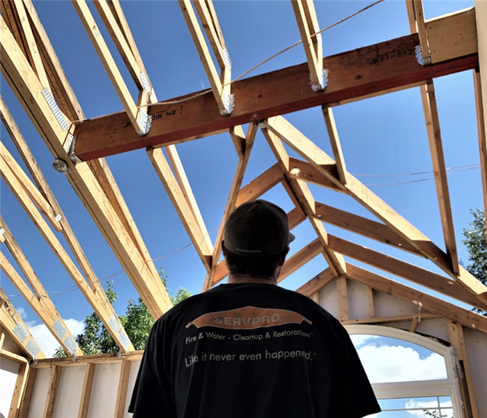 a man standing in a home with no roof during mid construction