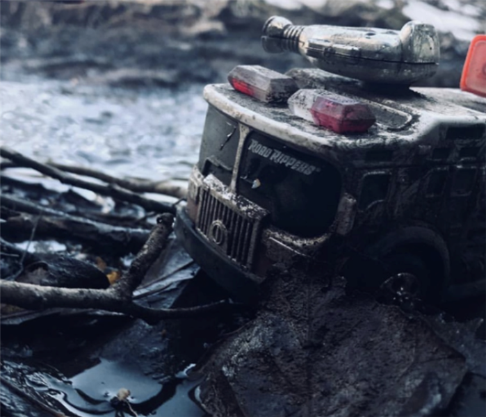 a small firetruck toy that has been charred with smoke and soot damge