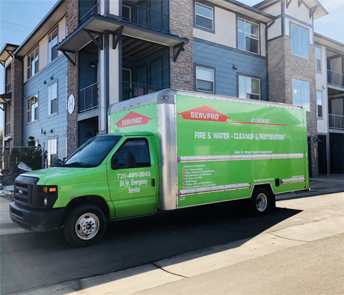 a green SERVPRO truck in front of an apartment complex