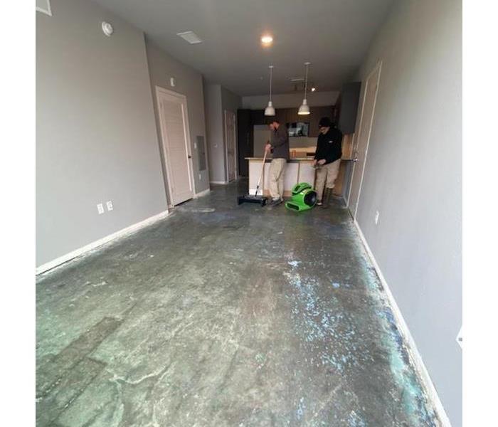 2 men removing adhesive from underneath flooring