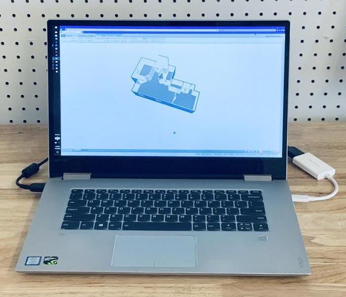 a computer on a desk with a construction plan pulled up
