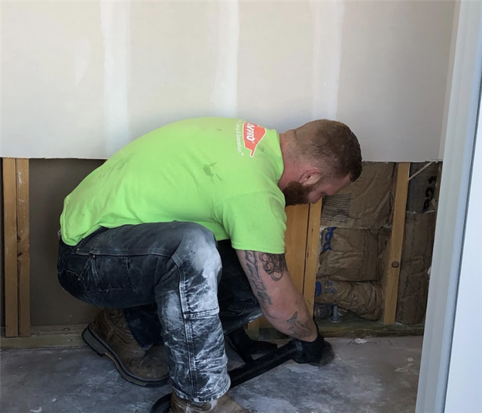 a SERVPRO worker vaccuming along the baseboards 