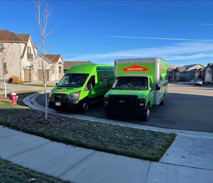 Two green SERVPRO vehicles parked in culdesac. 