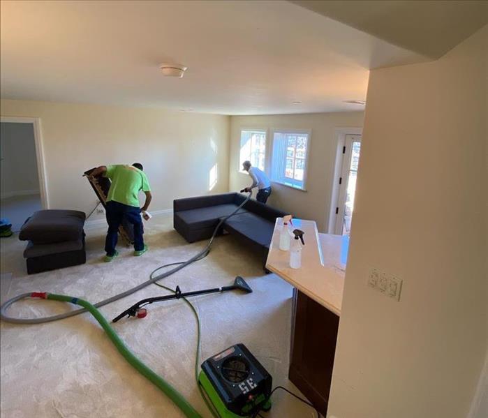 Two team members removing water in living room area.
