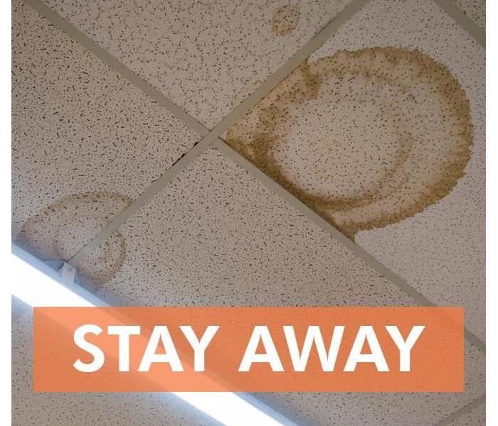Ceiling tile stained and words that say STAY AWAY