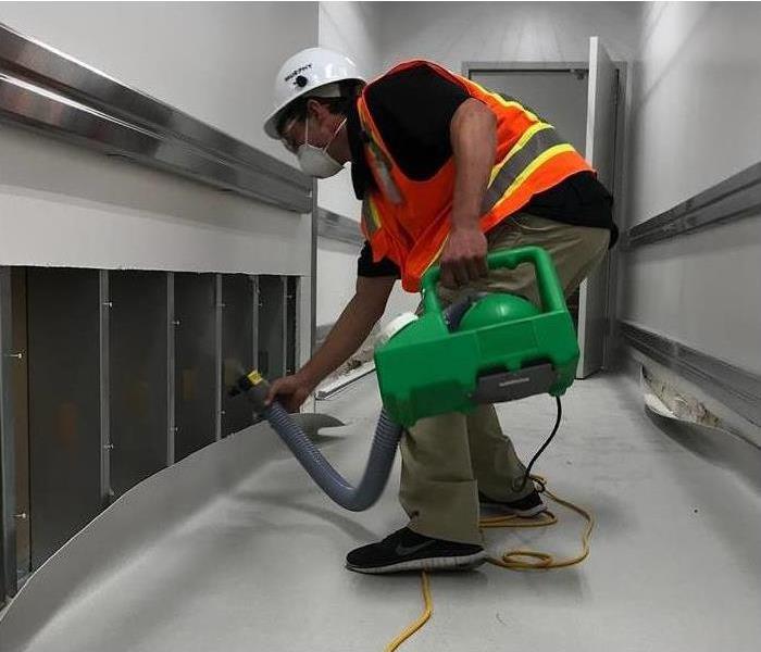 flood cut performed on drywall of commercial building, worker using drying equipment on wall